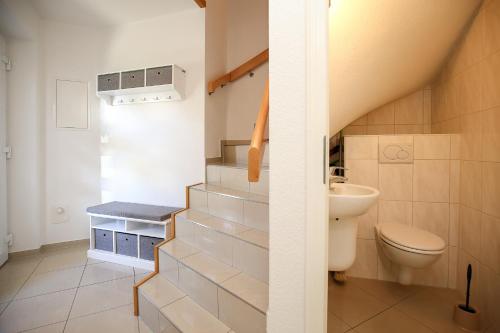 a bathroom with a staircase with a toilet and a sink at Sanddornweg Wohnung 13 b in Boltenhagen