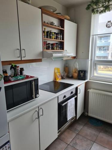 una cucina con mobili bianchi e un microonde nero di Charming apartment a Reykjavik