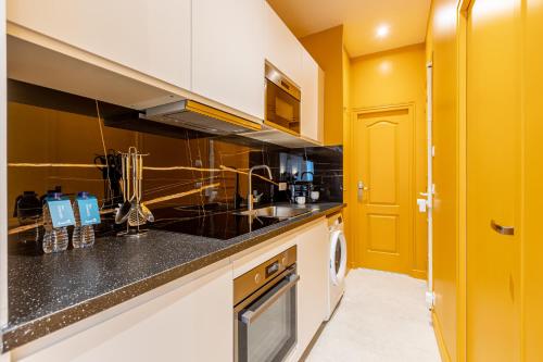 une cuisine avec des comptoirs noirs et une porte jaune dans l'établissement Sweett - Pavillon Madeleine, à Paris