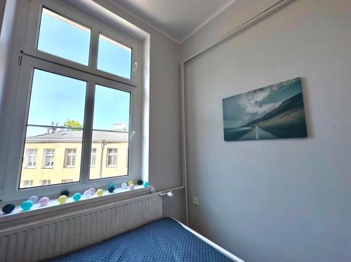 een kamer met een groot raam en een blauw tapijt bij MMRent One Way Room in Gdańsk