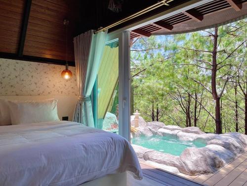 a bedroom with a bed and a view of a pool at Villa PaSon in Khao Kho