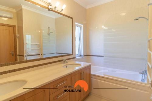 een badkamer met een wastafel, een bad en een spiegel bij #102 Villa Private Pool and Garden in Albufeira