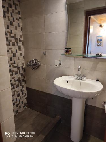 Astradeni luxury apartments Vootis في Páloi: حمام مع حوض ومرآة