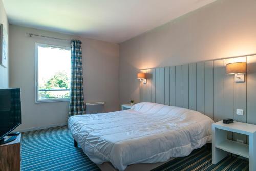 ein Schlafzimmer mit einem Bett und einem Fenster und einem Fernseher in der Unterkunft Les Thermes 427 - Appt avec piscine partagée in Concarneau