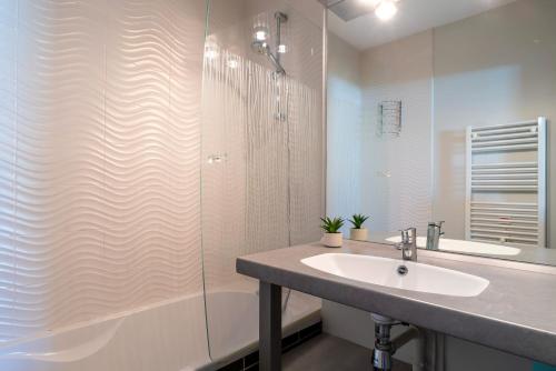 ein Badezimmer mit Waschbecken und Dusche in der Unterkunft Les Thermes 427 - Appt avec piscine partagée in Concarneau