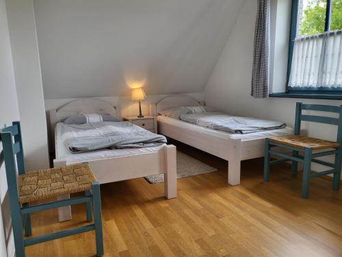 - 2 lits dans une chambre avec une chaise et une table dans l'établissement Ferienwohnung "Emil", à Sankt Peter-Ording
