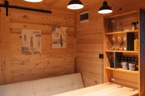 Habitación con pared de madera con banco y luces. en Tiny Heaven Cabin en Călimăneşti
