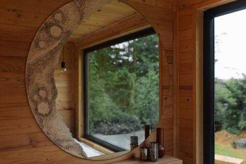 einen Spiegel in einer Blockhütte mit einem Fenster in der Unterkunft Tiny Heaven Cabin in Călimăneşti