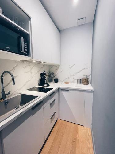 une cuisine blanche avec un évier et un micro-ondes dans l'établissement Le Loulou de La Rochelle, à La Rochelle