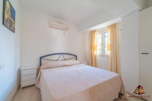 a white bedroom with a bed and a window at Porto Rotondo Central House in Porto Rotondo