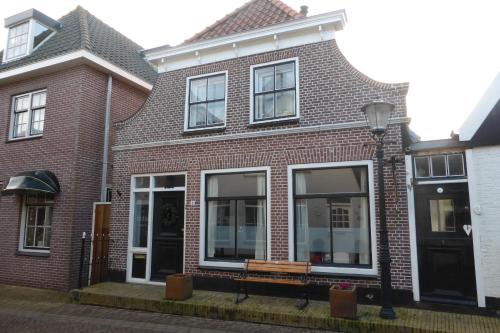 a brick house with a bench in front of it at B&B Bureau Warmoesstraat in Den Burg