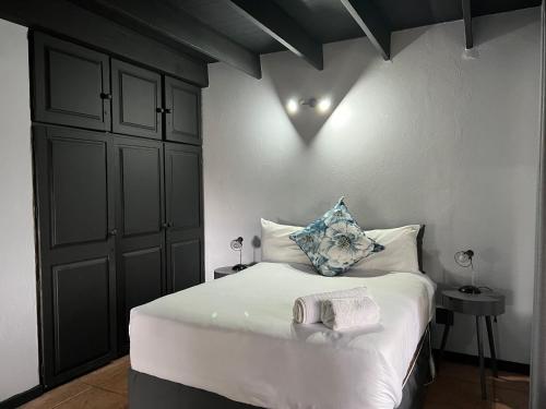 a bedroom with a bed with white sheets and blue pillows at Acoustic Guest House in Pretoria