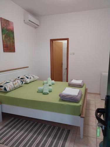 a bedroom with a green bed with towels on it at Sobe Kraft 2 in Živogošće
