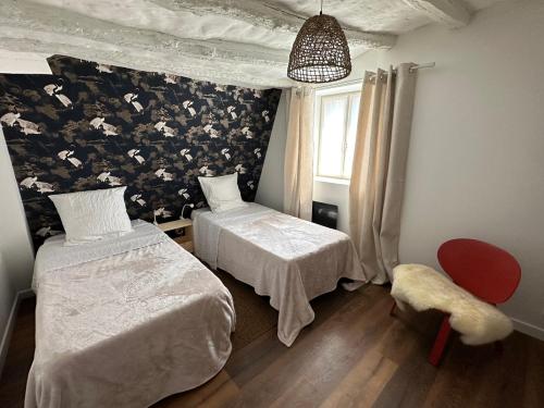 a bedroom with two beds and a floral wall at L'Echoppe en ville in Amboise