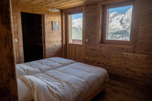 - une chambre avec un lit et une fenêtre avec des montagnes enneigées dans l'établissement Alpage la Grand Montagne 1858, au Grand-Bornand