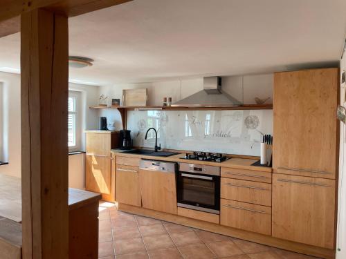 uma cozinha com armários de madeira e um forno com placa de fogão em Ferienhaus Beller Gehaichnis em Bell