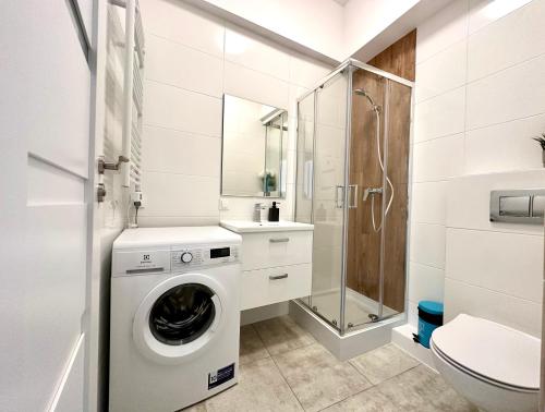 een badkamer met een wasmachine en een douche bij MMRent One Way Room in Gdańsk