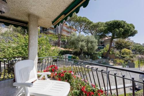 a white chair sitting on a balcony with flowers at Seaview - Deluxe apartment - Billiard - Pool in July and August - AC in the Bedrooms in Vallecrosia
