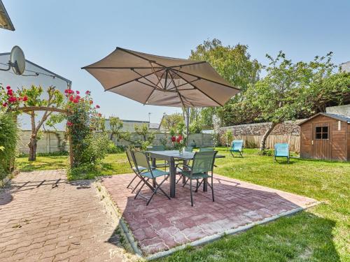 a table and chairs with an umbrella in a yard at Holiday Home Janomaine by Interhome in Cabourg