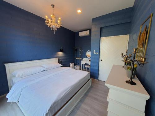 a blue bedroom with a large bed and a chandelier at Villa PaSon in Khao Kho