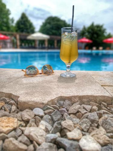 a drink and sunglasses sitting on a table near a pool at Hotel Storia in Čapljina