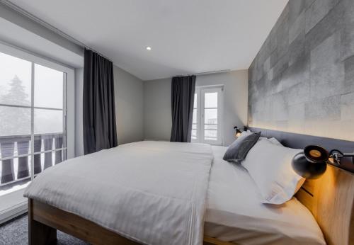 ein Schlafzimmer mit einem großen Bett und einem großen Fenster in der Unterkunft Villars Lodge in Villars-sur-Ollon