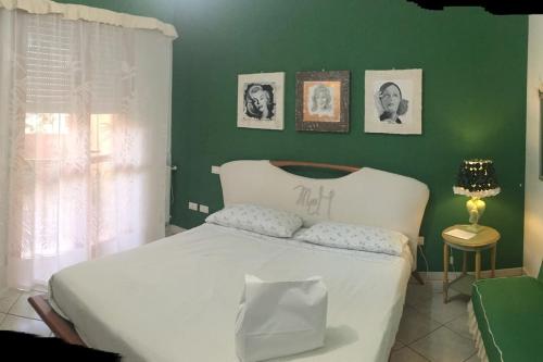1 dormitorio con cama blanca y pared verde en MonrealeHolidayHouse la tua casa a Cagliari, en Cagliari