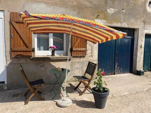 a table and chairs under an umbrella on a patio at L’évidence…. in Flavigny-sur-Moselle