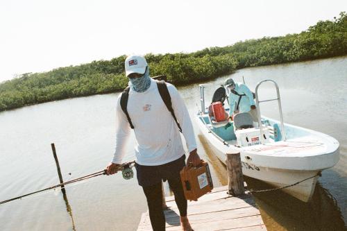 a man standing on a dock next to a boat at Grand Slam Fishing Lodge Tulum in Punta Allen