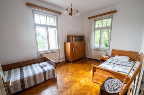 a bedroom with two beds and two windows at Socialist Experience in the City Center in Ljubljana