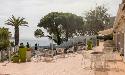 a patio with chairs and tables and the ocean at Ilunion Caleta Park in Sant Feliu de Guixols