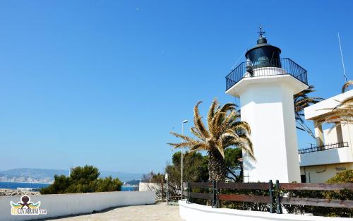 a lighthouse with a palm tree in front of it at Casa Mediterránia de Palamós amb piscina privada in Palamós
