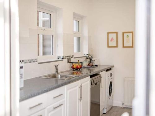 a white kitchen with two sinks and a dishwasher at Seagull Escapes - short walk to the beach in Scarborough