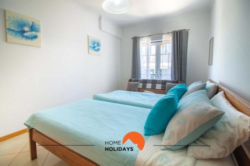Un dormitorio con una cama con almohadas azules y una ventana en #101 Kid Friendly with Pool, Private Park, 400 mts Beach en Albufeira
