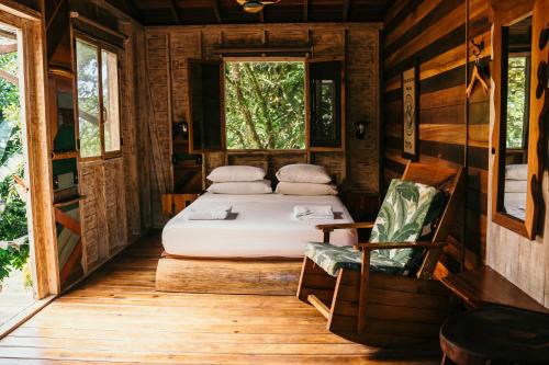 a bedroom with a bed and a chair and a window at Bambuda Lodge in Bocas Town