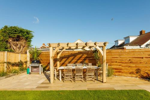 a patio with a table and chairs under a pergola at 4BR Beach House sleeps 10 - 5 mins walk to the Sea in West Wittering