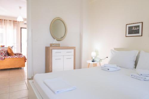 a white bedroom with a white bed and a mirror at Vereniki 2 in Kriopigi