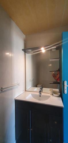 La salle de bains est pourvue d'un lavabo blanc et d'un miroir. dans l'établissement Appartement calme à quelques pas du port, à Port-Vendres