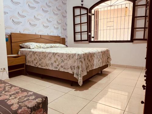 a bedroom with a bed and a window at Casa Cheia de Alegria e Sol in Peruíbe