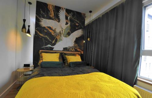 Un dormitorio con una cama amarilla con una pintura en la pared en APARTAMENT KRÓLOWEJ BONY- z garażem Centrum Gliwic, en Gliwice