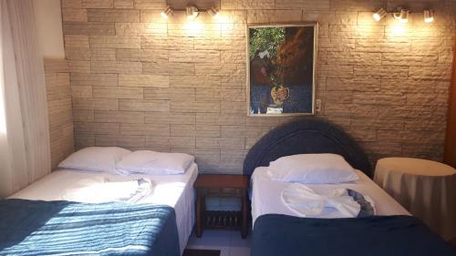 two twin beds in a room with a brick wall at Tu Casa in Asunción