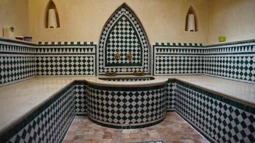 een badkamer met een groot bad in een kamer met zwarte en witte tegels bij casa bahia in Asilah