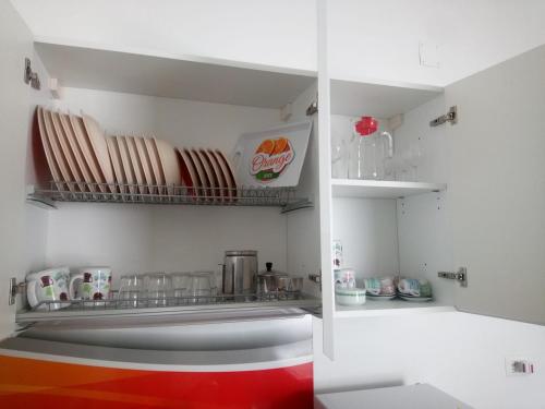 a kitchen with white walls and a shelf with dishes at La Torre Apartment by My Home Apulia in Torre Lapillo