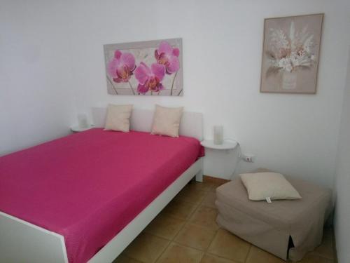 a bedroom with a pink bed and a ottoman at La Torre Apartment by My Home Apulia in Torre Lapillo