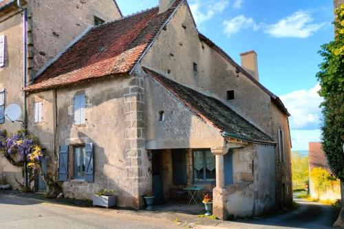 - un ancien bâtiment en pierre avec une table devant dans l'établissement Gîte privatif, proche nature et plan d'eau, à Charlanges