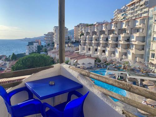 een blauwe tafel en stoelen op een balkon met een zwembad bij Bellavista Apartments Bougainville Bay in Sarandë