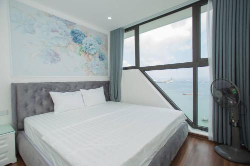 een slaapkamer met een bed en een groot raam bij Green Diamond Luxury Apartment 15A11 in Ha Long