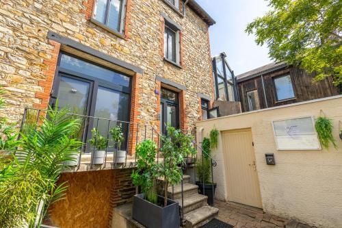 een bakstenen gebouw met een balkon met potplanten bij LIK APPARTS MABILAY in Rennes