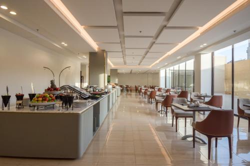 um restaurante com uma linha de buffet com mesas e cadeiras em Erfad Hotel - Riyadh em Riade