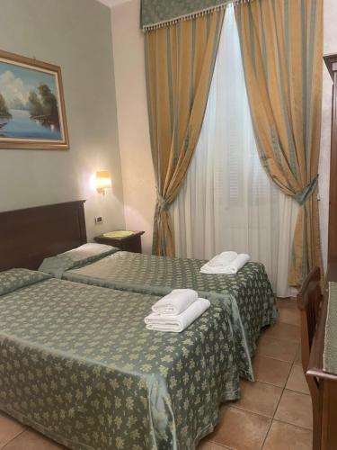 una camera d'albergo con due letti e una finestra di Bye Rome Guesthouse a Roma